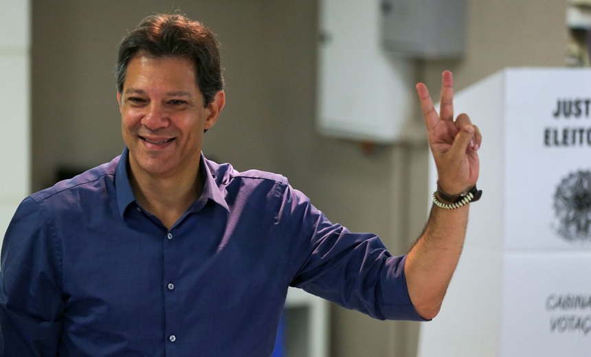 Com camisa azul, Haddad vota e faz sinal de vitória