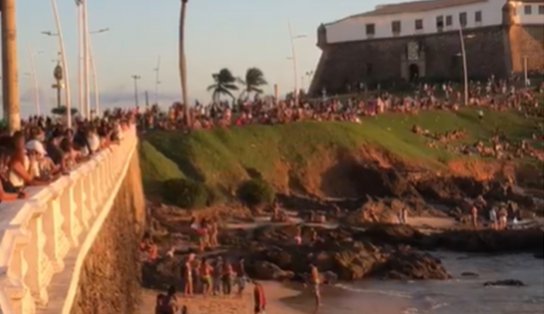 Público se aglomera para curtir a praia e ver pôr do sol no Farol da Barra; assista