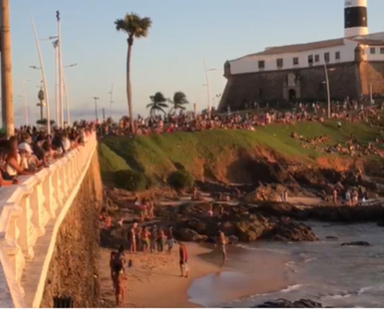 Público se aglomera para curtir a praia e ver pôr do sol no Farol da Barra; assista