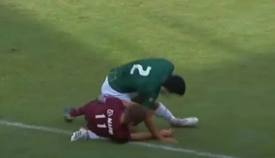 Jogador de futebol leva bolada, vai a nocaute, quebra perna de rival e é expulso; assista